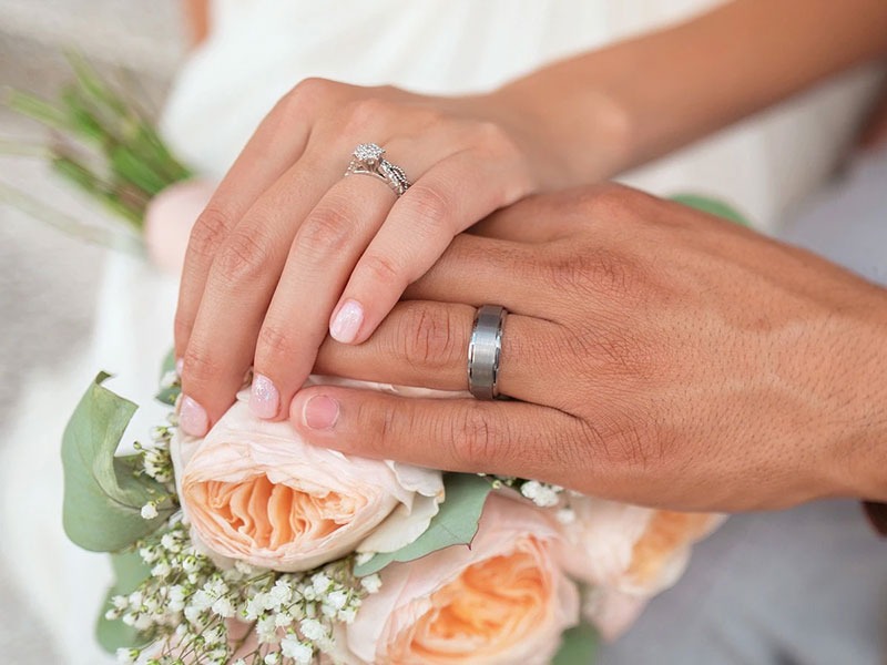 couple holding hands over a bouquet of flowers