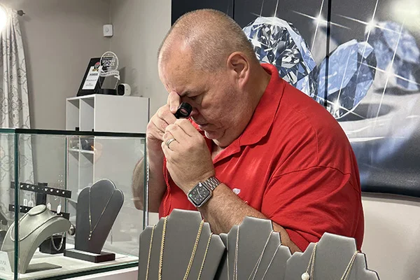 Don Walsh inspecting jewelry standing behind the counter in his shop